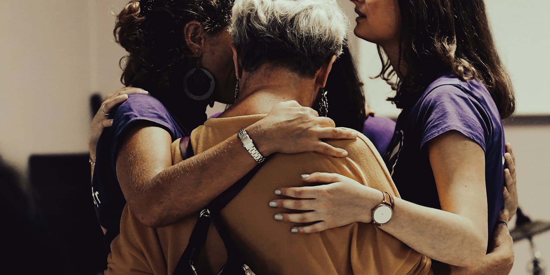 Three women embracing in a supportive group hug